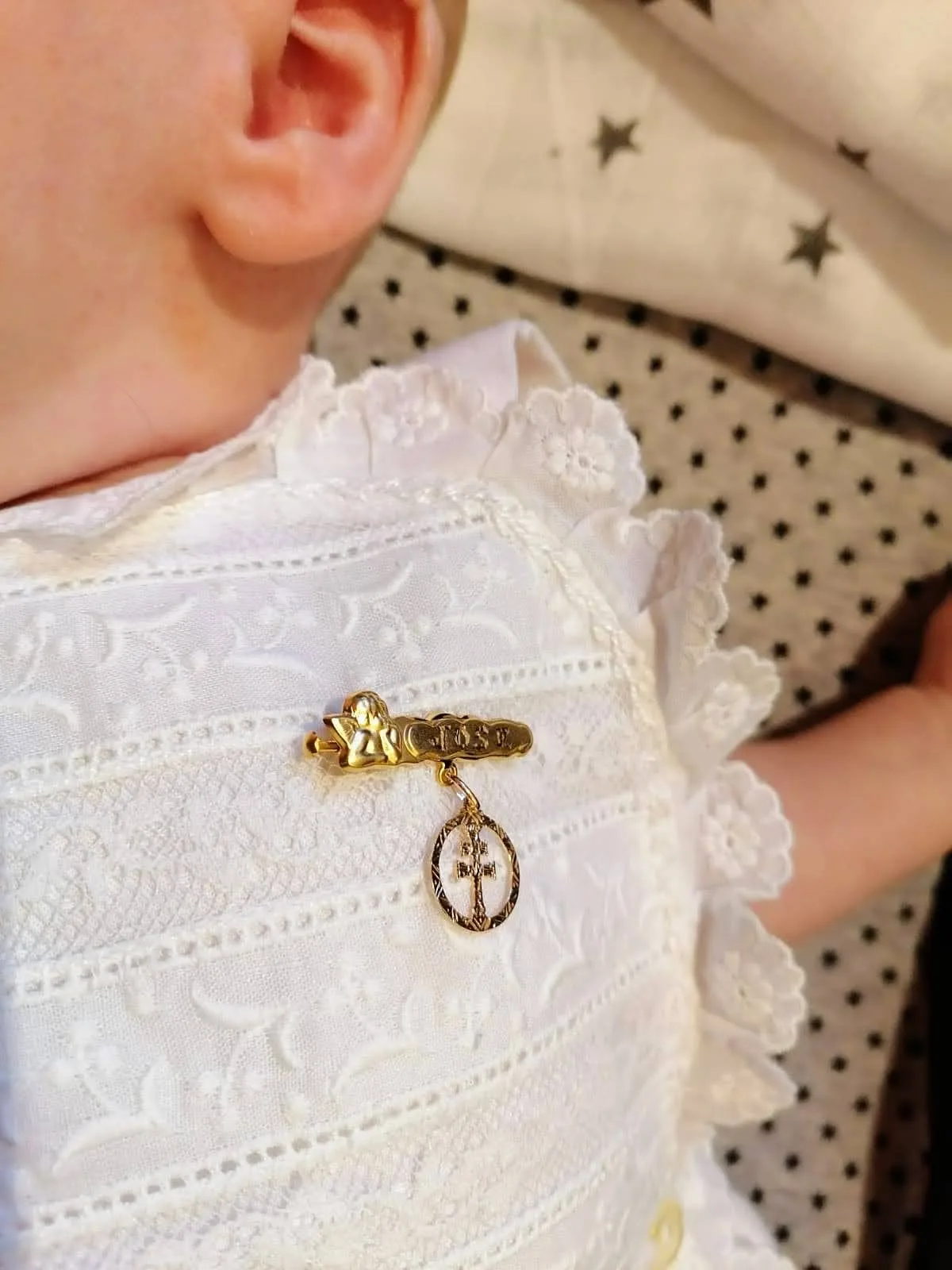 Bebé con un alfiler de oro con la Cruz de Caravaca
